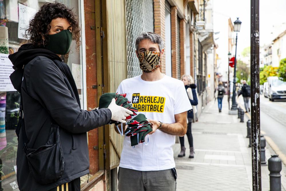 Voluntarios del grupo de apoyo de El Realejo MARTA GONZÁLEZ Con Ajuntamientos Albaicín como referencia organizativa, se articuló la actual Red de Cuidados de Granada con 10 grupos de voluntarios y voluntarias dispuestos a hacer la compra, ir a la farmacia a por medicamentos, tirar la basura o pasear la mascota por sus vecinos y vecinas. Ajuntamientos es una plataforma ciudadana con más de cinco años de trayectoria en la articulación de reivindicaciones barriales. Muchos de los casos que atiende la red son a demanda de familiares que viven en la Granada metropolitana —o incluso en otras provincias— y contactan para que asistan a sus seres queridos. “Tengo a mi madre ya mayor viviendo sola en el Albaicín; me gustaría que alguien le pudiera llevar la compra”. Este caso se está dando a menudo, según explica Marina de Ajuntamientos Albaicín. “Otros son específicos del barrio, como tirar la basura de una mujer mayor en el Sacromonte porque su contenedor está dos calles por encima de la suya y, con las cuestas típicas de la zona y el empedrado, le resulta imposible”. redes apoyo coronavirus Granada 11 Cartel en el Paseo de los Tristes anunciando el grupo de apoyo de el Albaicín. MARTA GONZÁLEZ ¿CÓMO LLEGAR A QUIEN LO NECESITA? La mayoría de grupos mantiene contacto y colaboración con Servicios Sociales, centros de salud, ONG y entidades sociales, algo que consideran esencial. “Nos están llamando de ONG y Servicios Sociales donde se encuentran desbordados y nos derivan algunos casos. Sentimos que, al estar respaldados por entidades conocidas que inspiran más confianza a los usuarios, se sienten más seguros y todo funciona mejor”, nos comenta Laura, de Centro-Sagrario. Se enfrentan a dos grandes retos: el miedo generado por la desconfianza, como explica Carlos de Camino de Ronda: “En esta zona hay muchas personas mayores que tienen recelo de engaños y estafas, y que desgraciadamente son susceptibles de ser estafados, necesitan saber que nosotros estamos organizados y no lo vamos a hacer”; y la necesidad de difusión, “hemos puesto carteles en nuestros edificios, farmacias y comercios, también en redes sociales, pero necesitamos que los medios de comunicación compartan esta iniciativa más a menudo, sobre todo radio y televisión”. redes apoyo coronavirus Granada 10 En tiempos de coronavirus, el cuidado colectivo de las personas vulnerables es imprescindible. MARTA GONZÁLEZ Zona norte, Albaicín y Zaidín son los grupos que, en ese orden, cuentan con una red de cuidados más completa porque está reforzada por un trabajo previo de colaboración con la administración y el tejido asociativo y social de los barrios. En zona norte el grupo de ayuda ha sido organizado por estudiantes que residen en el distrito con la inquietud y el ánimo de colaborar e implicarse en un barrio del que se sentían desconectados. Cuenta con casi 60 personas, y muchas de ellas participaban ya en otras iniciativas vecinales como “No más cortes de luz”. Granada cortes de luz 01 Confinamiento a oscuras en la Zona Norte de Granada ALESSIO INCORVAIA En Albaicín, Ajuntamientos acompañó en su momento la defensa y la estabilización de la plantilla de profesionales del centro de salud del barrio, que los ha consolidado en un entorno de confianza y cercanía con la vecindad, logrando conexión y soporte para el desempeño del apoyo y los cuidados. Para dar a conocer las iniciativas de ayuda mutua que se han desarrollado en el barrio han puesto en marcha una emisora de radio: “La Albaicinera”. El grupo del Zaidín ha sido impulsado desde el Colectivo la Ribera y apoyado por la asociación Granada Acoge y el Centro Sociocultural de Adultos. Es muy numeroso: casi 200 personas que comparten dos chats en whatsapp, uno para tratar específicamente los casos de ayuda y otro donde compartir información, inquietudes y promover el debate. “Esta crisis ha evidenciado la necesidad de reconstruir el tejido social y vecinal; ahora tenemos que hacerlo deprisa y corriendo”, afirma José Juan, del Colectivo La Ribera. redes apoyo coronavirus Granada 9 Grupo de voluntarios de El Zaidín en una jornada de entrega de mascarillas MARTA GONZÁLEZ MANTENER Y DOTAR DE RECURSOS A LOS CENTROS DE SALUD Y LOS SERVICIOS SOCIALES Isabel, enfermera en el centro de salud de Cartuja, nos cuenta que articuló con el grupo de ayuda de norte la organización de una especie de “Teléfono de la Esperanza”: “Desde los centros de salud hacemos un seguimiento del estado de los mayores de 65 años, controlamos la evolución de los que presentan patologías, los más frágiles. Sin embargo, hay muchas personas mayores que no están enfermas, ni física ni psicológicamente, pero están muy solas, y es de mucha ayuda que haya alguien que pueda llamar de forma regular: ¿Estás bien?, ¿Necesitas algo?”. La atención primaria de salud desempeña unas funciones que no se pueden suplir desde ningún otro espacio: atención telefónica de los pacientes, atención presencial, visitas domiciliarias y coordinación sociosanitaria en colaboración con Servicios Sociales, entidades sociales y ahora también con los grupos de ayuda y cuidados. Por su parte, la ejemplar plataforma de entidades sociales de norte trabaja a su vez con Servicios Sociales, centros de salud y Junta de Andalucía. Ahora, con esta crisis y aprovechando esta ayuda “extra”, han incorporado en su red de actuación al grupo de ayuda. La labor de la plataforma es la de la puesta en común de los recursos activos y organizarse para que la gente conozca lo que tiene a su disposición. Les parece un error cerrar los centros de Servicios Sociales y los centros de salud, que son los que deberían centralizar todas las actuaciones “Si las entidades bancarias trabajan y el sistema sanitario también, ¿por qué no pueden hacerlo los servicios sociales?, son tan esenciales como los servicios de salud. Si se da una situación extraordinaria, se deben dotar de recursos extraordinarios y organizarse de forma extraordinaria”, nos explica Sonia. ¿Qué piden? Que las instituciones faciliten recursos a través de los SS.SS. a las familias para cubrir sus necesidades básicas; que doten de equipamientos a los centros de salud, los SS.SS. y las personas que trabajan con familias vulnerables; que se habiliten números de teléfono gratuitos para la atención social (“hay personas que ya no tienen ni saldo en el teléfono para llamar”); y que se atiendan y se solucionen los cortes de luz, “un factor agravante que le confiere un sentido violento al hecho de quedarse en casa sin suministro, eliminando la posibilidad incluso de almacenar alimentos frescos”. Precisamente en este sentido, y en representación de 62 organizaciones, la Asociación Pro Derechos Humanos de Andalucía (APDHA) y la Asociación Gitana Anaquerando presentaron ante las Consejerías de Salud y de Igualdad de la Junta de Andalucía y el Parlamento andaluz una instancia pidiendo que durante la crisis se mantengan abiertos los centros de salud de la comunidad autónoma y que los Servicios Sociales comunitarios se refuercen, especialmente en barrios de necesidad de transformación social y en zonas rurales. redes apoyo coronavirus Granada 8 Entrega de comida en el Hogar del Corazón de María MARTA GONZÁLEZ POBREZA SOBREVENIDA, LAS CHAPUZAS SE HAN TERMINADO Con la crisis del COVID-19, familias muy vulnerables, gente que sobrevivía en un estado de subsistencia se encuentra de un día para otro en un estado de pobreza sobrevenida; “personas que vivían de la prostitución, de la recogida de chatarra, la venta ambulante, de hacer chapuzas, manteros... que de un día para otro no pueden conseguir los 5, 10 eurillos que les permitían subsistir”, nos dice Sonia, de la plataforma de entidades sociales de zona norte. Los grupos de ayuda y cuidados se sienten impotentes en estos casos, insisten en la necesidad de articularse con profesionales: “Nosotros podemos hacer distintas tareas, también la de acompañamiento telefónico, pero no podemos atender problemas estructurales”, dice Isidro, del grupo de ayuda en la Chana. C, trabajadora del Área de Derechos Sociales de Granada, explica que los profesionales de los Servicios Sociales teletrabajan desde casa “a destajo” sin apenas recursos. “Ahora mismo se están tramitando rentas mínimas de urgencia. Lo que más se demanda son alimentos, los niños tienen asistencia alimentaria básica con el plan PRIA de Salud y Garantía Alimentaria, y los adultos deberían recibir una renta mínima directa; porque no sólo se necesita comida: también artículos de aseo, higiene y limpieza. Así evitaríamos la manipulación de dinero y comida por varias personas en los bancos de alimentos. Los trámites deben ser más ágiles y efectivos, y el visto bueno de los políticos también. Tenemos que cubrir las necesidades básicas de todas las familias. Si hay carencia de lo necesario, vamos a tener todavía más problemas”. redes apoyo coronavirus Granada 12 Cartel de atención y ayuda a personas mayores en un buzón. MARTA GONZÁLEZ EN OTRAS CRISIS SE RESCATARON BANCOS, AHORA DEBEMOS PROTEGER LA VIDA Y RESCATAR PERSONAS Todos estos agentes de los servicios de atención social coinciden en la necesidad de reclamar el lugar que los cuidados merecen en nuestra sociedad. Esperan que el mensaje de la pandemia —esta bofetada en plena cara— nos haga pensar y reaccionar. El mundo ha parado, ¿cómo queremos reconstruirlo cuando se ponga en marcha? Estas redes, estas estrategias de ayuda mutua y cuidados se deben conservar y consolidar para que armen un entramado más fuerte y más amplio. Cuando todo esto acabe, necesitamos un debate colectivo donde poner en común las experiencias y retos, todo lo aprendido, saberes con los que seguir creciendo y hacer frente a lo que vendrá después, que queremos sea bueno y lo queremos construir juntos. CONTACTO Guía de recursos sociales en Granada: lista con centros sanitarios, centros de Servicios Sociales, entidades sociales y grupos de ayuda de Granada. Red de cuidados de Granada: plataforma online de cuidados entre vecinos y vecinas de los barrios de Granada.